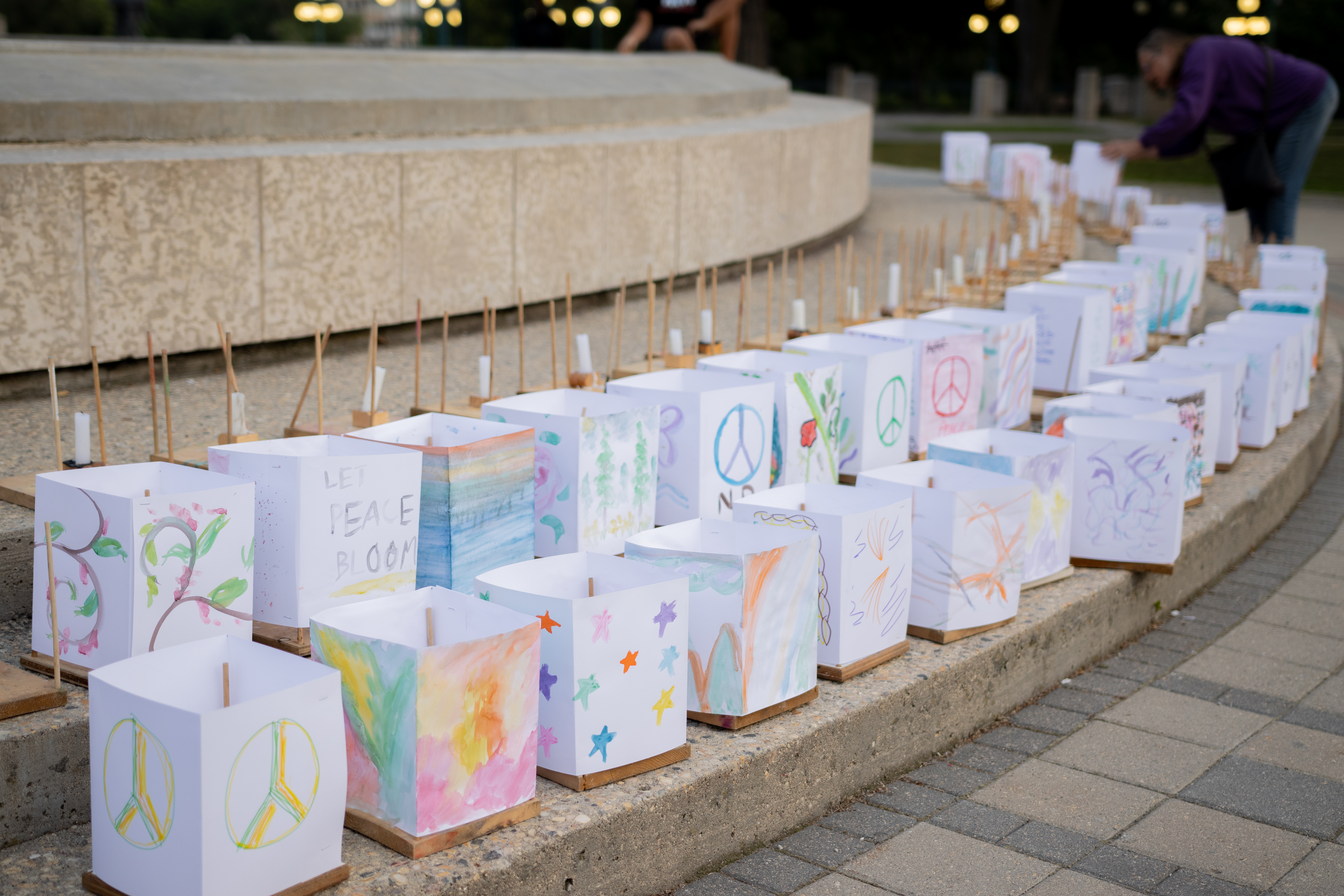 Two lines of square paper lanterns decorated with messages encouraging peace 